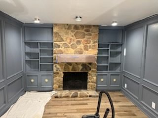 Custom-painted built-in cabinetry around a stone fireplace
